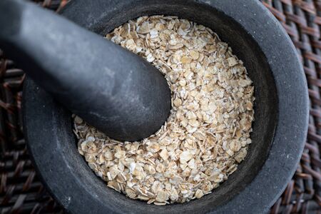 Close-up with crushed whole oats. In stone mortar. Rustic appearance.の写真素材