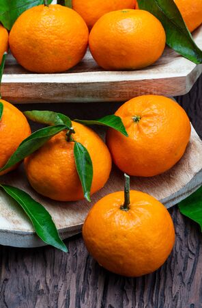 Fresh and raw tangerines with green leaves. Rustic appearance. On wooden background.の写真素材