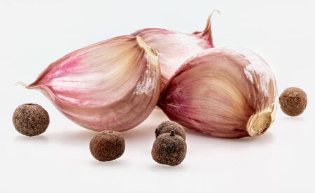 Group of red garlic cloves and black pepper balls. Isolated on white background.