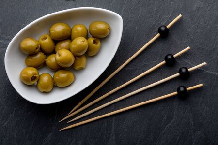 Bowl with anchovy stuffed olives. On black slate. Blackboard. Toothpick. Top View.の写真素材
