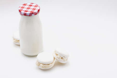 Milk bottle with delicious white macarons. Copy space. Isolated on white background.の写真素材