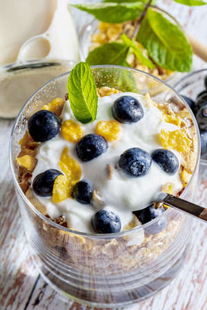 Delicious dessert of blueberries, yogurt and cereals (muesli). Refreshing and healthy breakfast of yogurt, blueberries, dried fruits and dried fruits. Top view. Macro close-up.の写真素材