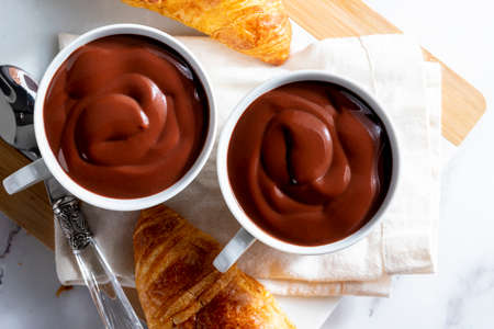 Appetizing breakfast with two delicious cups of thick, drinkable hot chocolate, along with croissants. Homemade look.の写真素材