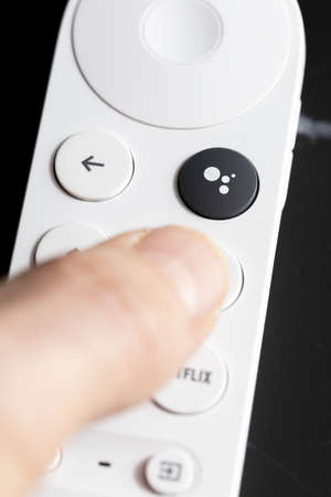 SPAIN - March 3, 2021. Close-up of the Google Assistant button on the remote control for Chromecast with Google TV in one handのeditorial素材