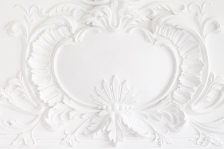 Beautiful ornate white decorative plaster mouldings in studio. The white wall is decorated with exquisite elements of plaster stucco.の写真素材