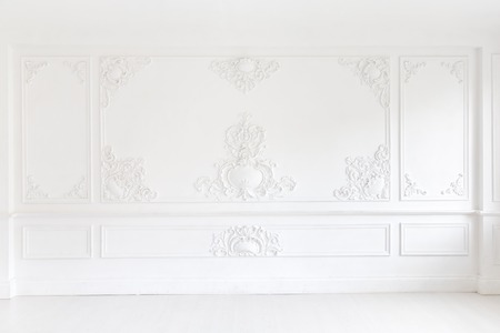 Beautiful ornate white decorative plaster mouldings in studio. The white wall is decorated with exquisite elements of plaster stucco.の写真素材