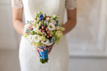 The bride is holding a wedding bouquet in her outstretched hands.の写真素材