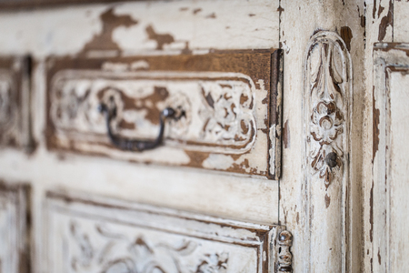 Vintage chest of drawers with carving white color with fading and metal handle. Close-up. Selective focusの写真素材