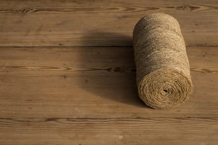 A roll of twine on a wooden background. Selelective focus. Close-up. Free space for text.の写真素材