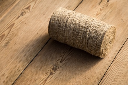 A roll of twine on a wooden background. Selelective focus. Close-up. Free space for text.の写真素材