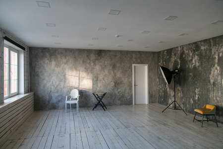 Modern light loft-style room with designer chairs and lighting. Gray walls with the texture of the concrete. Wooden floor.の写真素材
