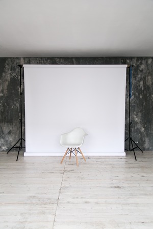 The working space of the photo studio with a white paper background and chair.の写真素材