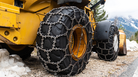 Front loader for snow removal with metal snow chains on wheels. Snow removal in the mountains.の写真素材