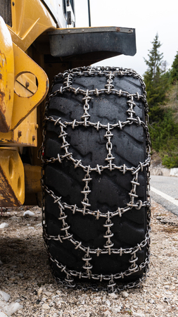 Front loader for snow removal with metal snow chains on wheels. Snow removal in the mountainsの写真素材