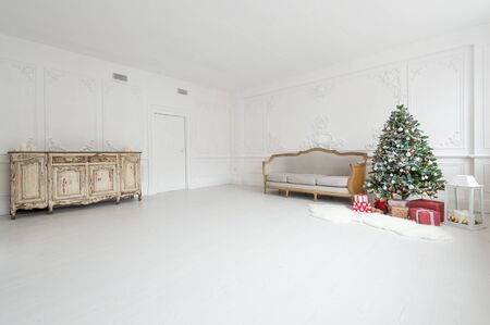 Luxurious bright interior with stucco walls, christmas tree, vintage chest of drawers and sofa.の写真素材