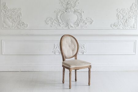 Living room in antique style. Vintage chair against the wall with a bas-relief of plaster stucco. Selective focus.の写真素材