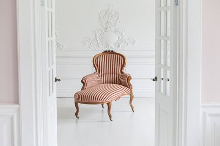 Vintage sofa with wood carvings in a luxurious light interior with stucco on the walls. Selective focus.の写真素材