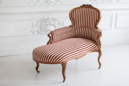 Vintage sofa with wood carvings in a luxurious light interior with stucco on the walls. Selective...