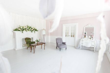 Bright luxurious interior of the living room with fireplace and armchairs decorated with flowers.の写真素材