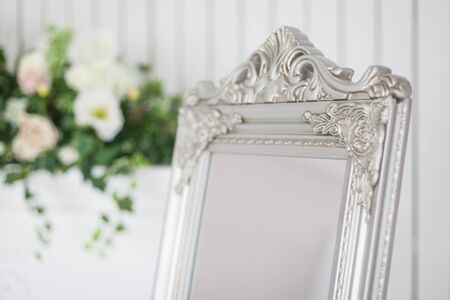 Mirror in classic bright interior with fireplace and armchair. Spring interior decoration with flowers.の写真素材
