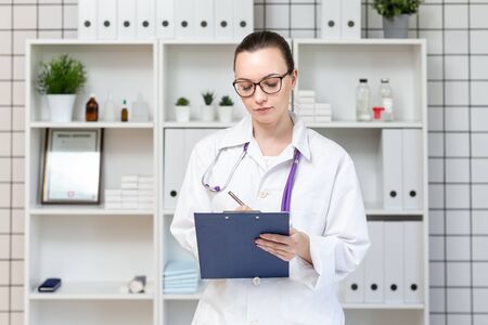 Beautiful woman veterinarian. Veterinary clinic. Holding a tablet and a pen.の写真素材