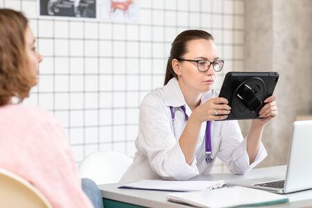 Veterinarian examines the results of tests on the tablet. Close up.の写真素材