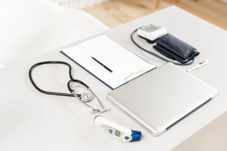 Stethoscope, measuring blood pressure and laptop on wooden desk for analysis of medical results.の写真素材