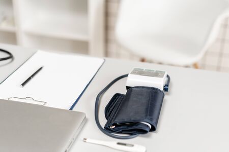 Workplace of doctor with laptop, stethoscope and notebook on wooden table in the office. Blood Pressure Monitor. Medical equipment. Cardiac diagnosis. vintage tone.の写真素材