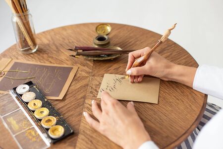 Young beautiful girl in a luxurious interior writes a love letter to her boyfriend. Romantic mood on Valentines Day. Soft focus. Close-up.の写真素材
