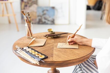 Young beautiful girl in a luxurious interior writes a love letter to her boyfriend. Romantic mood on Valentines Day. Soft focus. Close-up.の写真素材