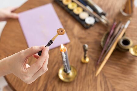 A calligrapher woman makes a wax seal on the envelope. Close-up. Soft focus.の写真素材