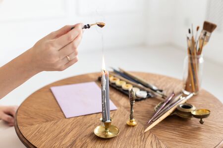 A calligrapher woman makes a wax seal on the envelope. Close-up. Soft focus.の写真素材