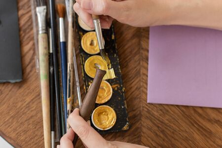 The artist is preparing to work. Applies paint to the brush. Close-up. The atmosphere of the creative workshop.の写真素材