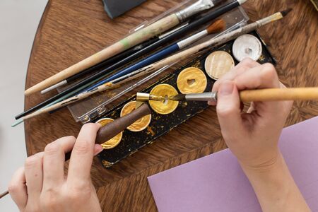 The artist is preparing to work. Applies paint to the brush. Close-up. The atmosphere of the creative workshop.の写真素材