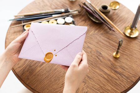 Female hands hold an envelope with a letter and a surgut seal. Gift Certificate. Wedding invitation. Soft focus.の写真素材