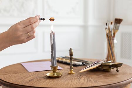 A calligrapher woman makes a wax seal on the envelope. Close-up. Soft focus.の写真素材