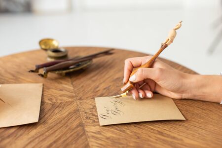 Hand holding ink pen. The concept of storytelling. The girl writes a letter at the table. Soft focus. Close-upの写真素材