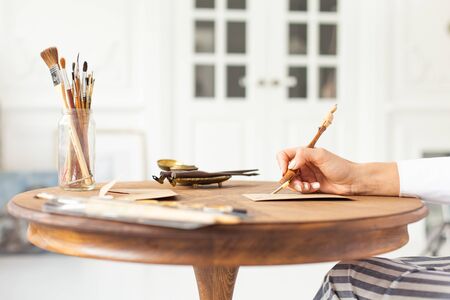 Young beautiful girl in a luxurious interior writes a love letter to her boyfriend. Romantic mood on Valentines Day. Soft focus. Close-up.の写真素材