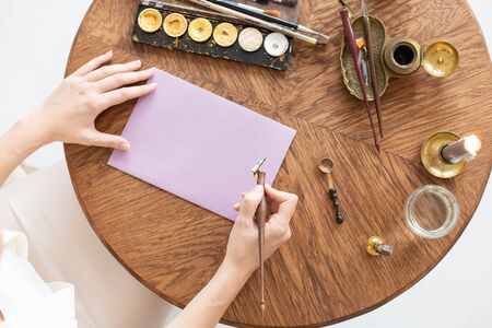A copywriter writes a story. A hand is holding a ink pen in front of a blank sheet. Free space for text. Soft focus.の写真素材