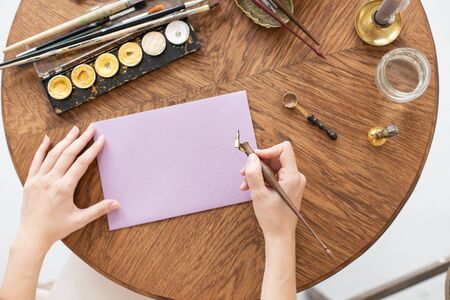 A copywriter writes a story. A hand is holding a ink pen in front of a blank sheet. Free space for text. Soft focus.の写真素材