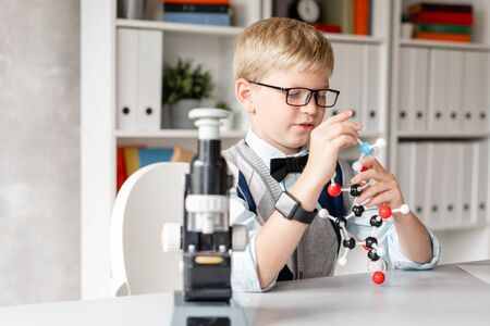 Cute child in casual clothes assemble a model of a chemical elementの写真素材