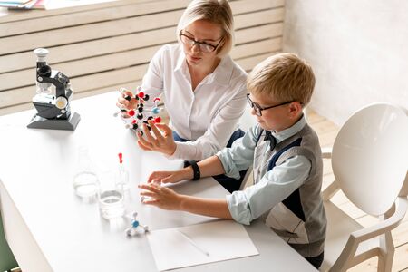 Young schoolboy attentively listen his tutors lesson of chemistryの写真素材