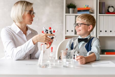Confident tutor explaining to her little student what every piece of model of element meansの写真素材