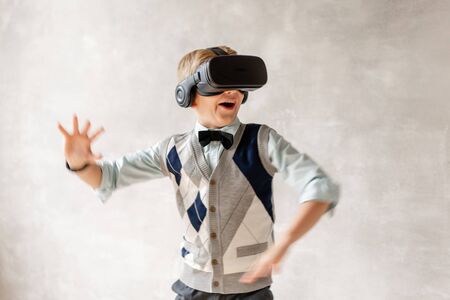 Little boy in VR glasses looks up and laughの写真素材