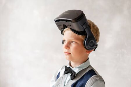 Young boy in VR helmet posing on background of gray wallの写真素材
