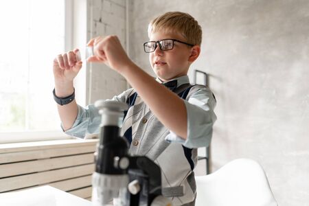 Young boy preparing samples for examination under microscopeの写真素材