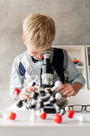 Little schoolboy in casual clothes looks in microscopeの写真素材