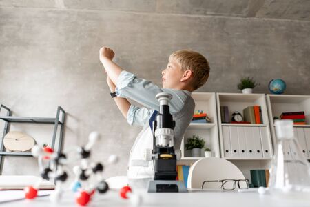 Little boy in casual clothing looks at sun through the transparent glassの写真素材