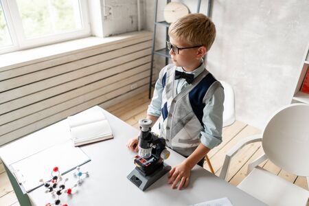 Little schoolboy in casual clothes looks in microscopeの写真素材