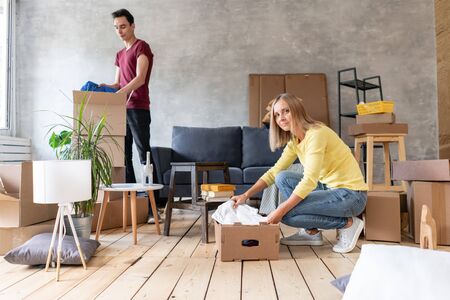 Happy smiling couple moving in a new house and unpacking cartons boxes, relocation and renovation conceptの写真素材
